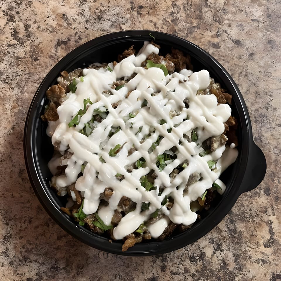 La Carreta's Mexican dish with meat, cilantro, onions, and white sauce in a black bowl.