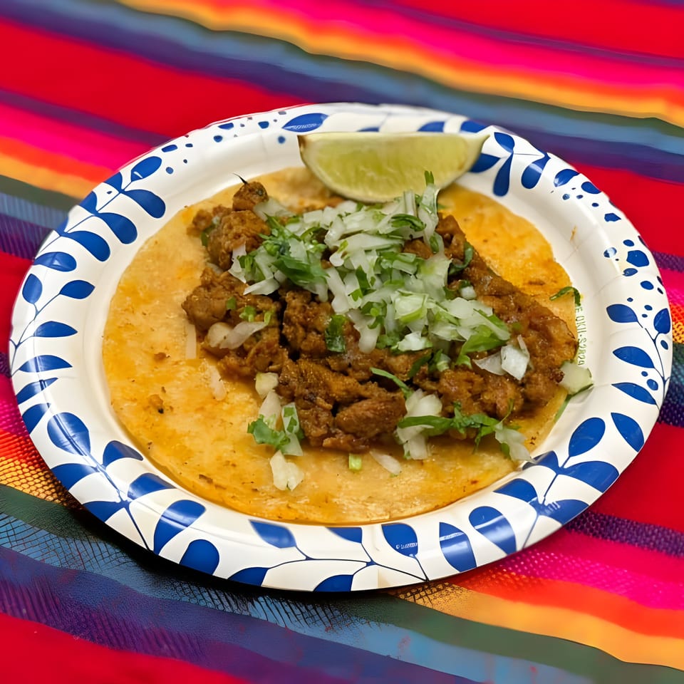 La Carreta's al pastor taco on a paper plate with lime, onions, and cilantro.